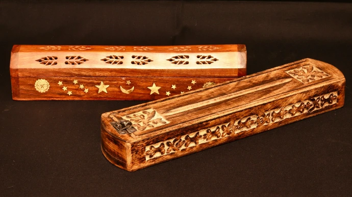 two wooden boxes with designs on them on a black surface